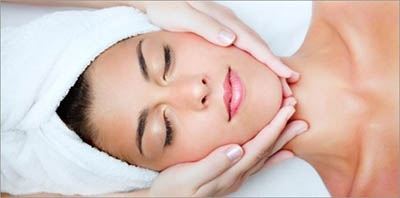 Woman with face in a towel getting a facial massage.